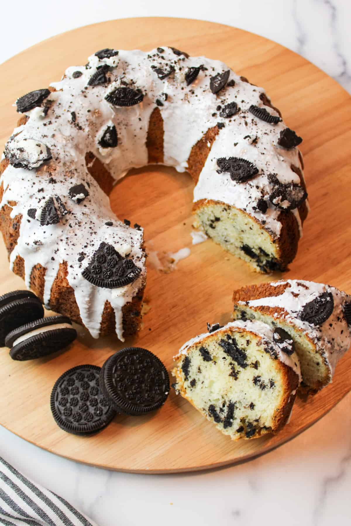 sliced oreo bundt cake on a wooden surface with oreo cookies.