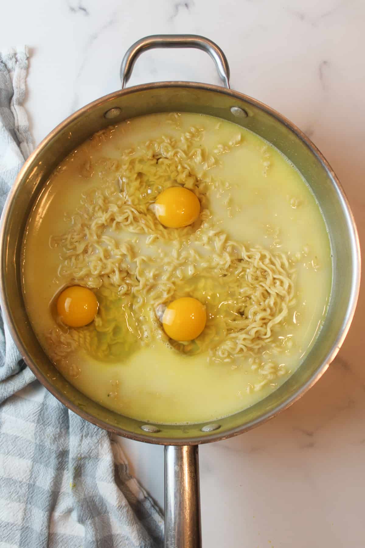 raw eggs on cooked ramen in a large pan
