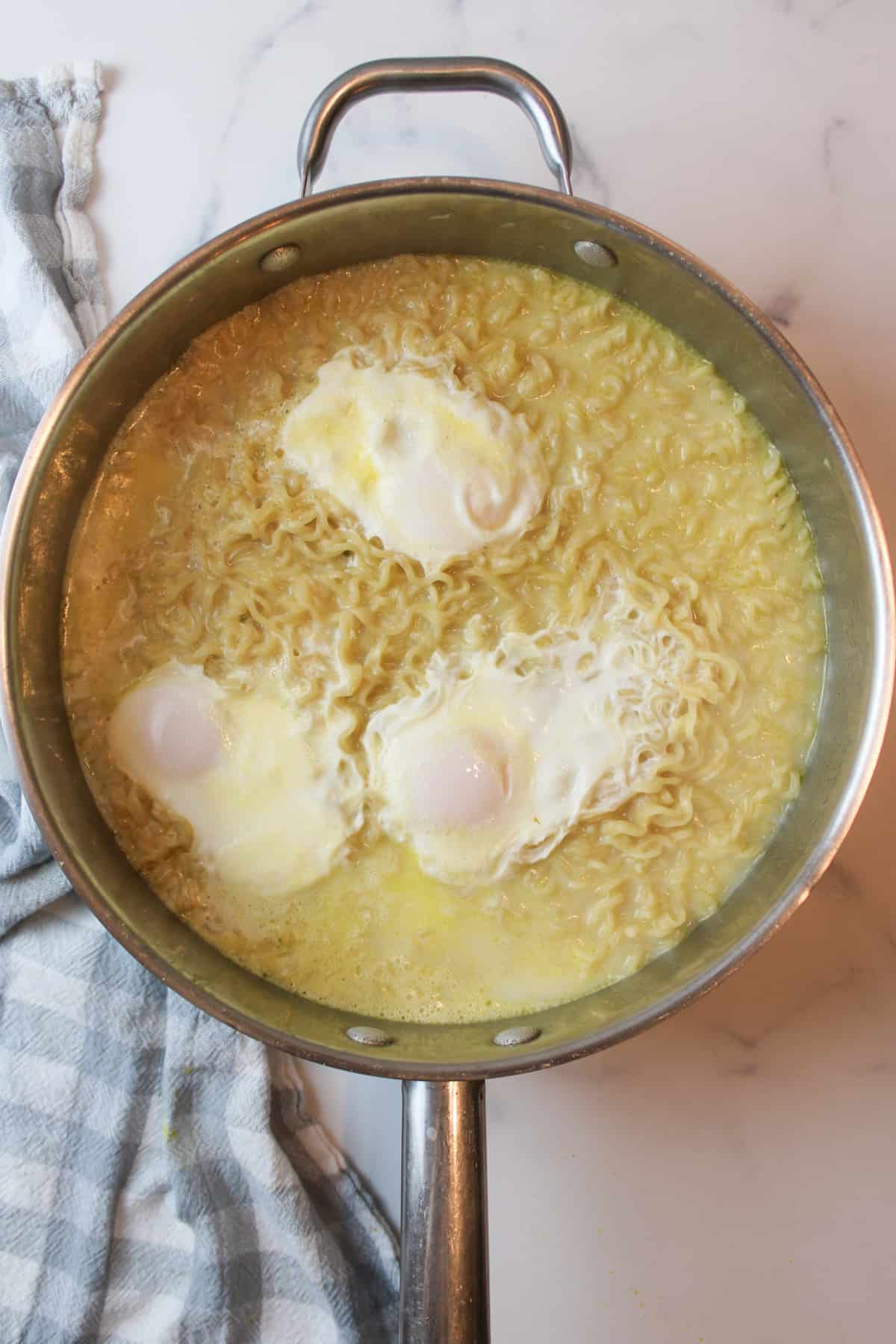 poached eggs on cooked ramen in a large pot.