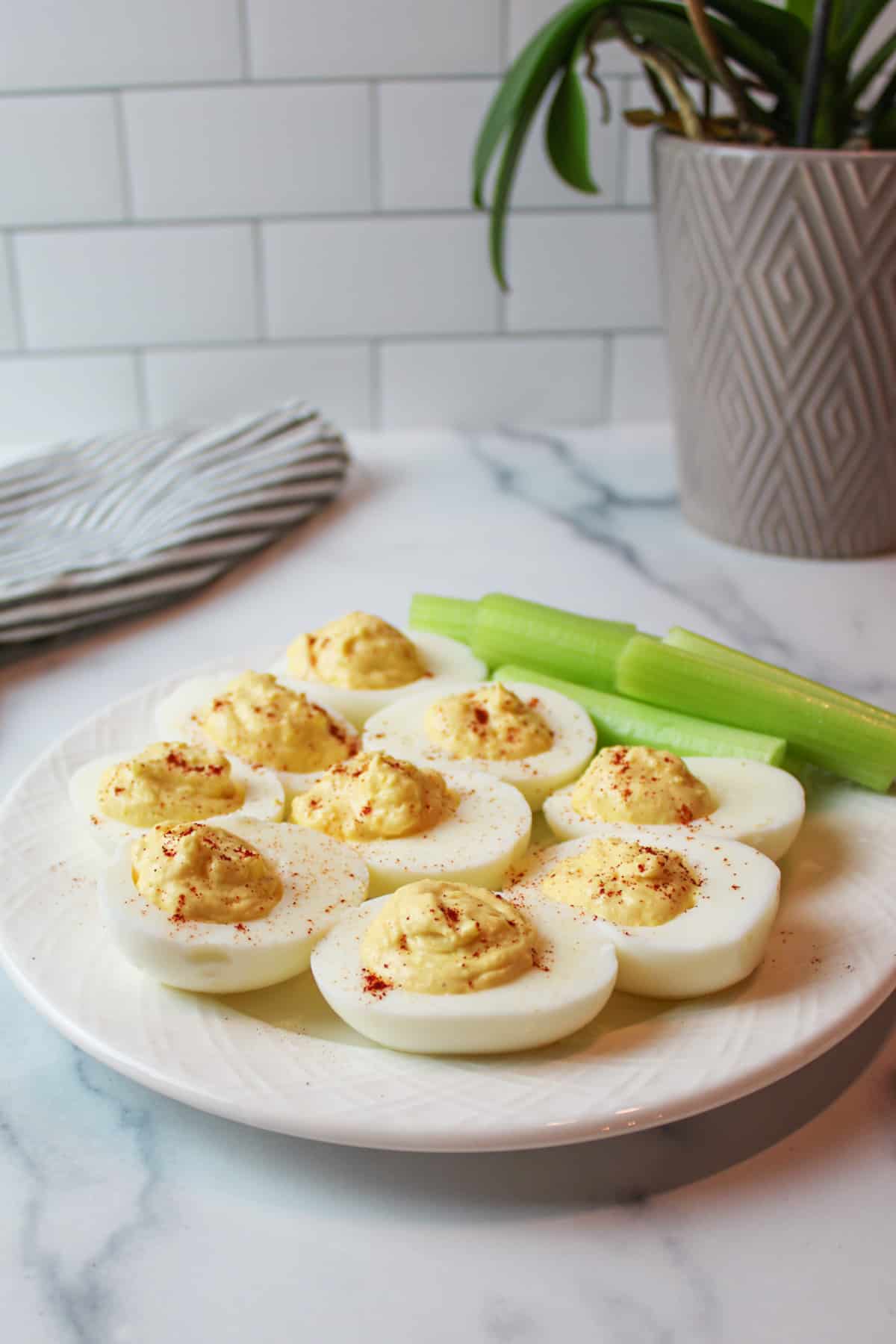 side view of a plate full of spicy deviled eggs with celery