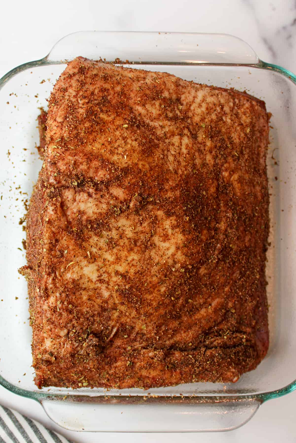 seasoning covered beef roast in a roasting pan.