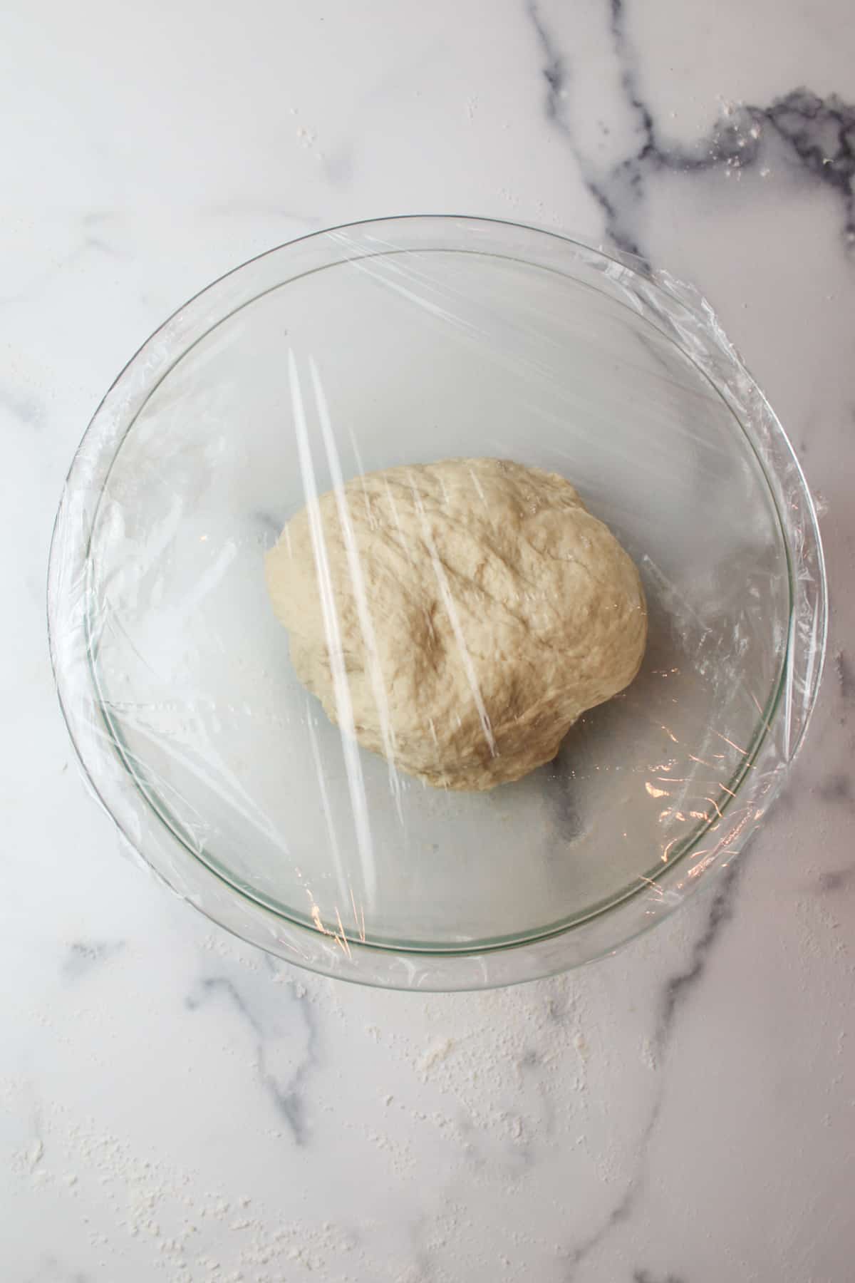 ball of dough in a mixing bowl topped with plastic wrap