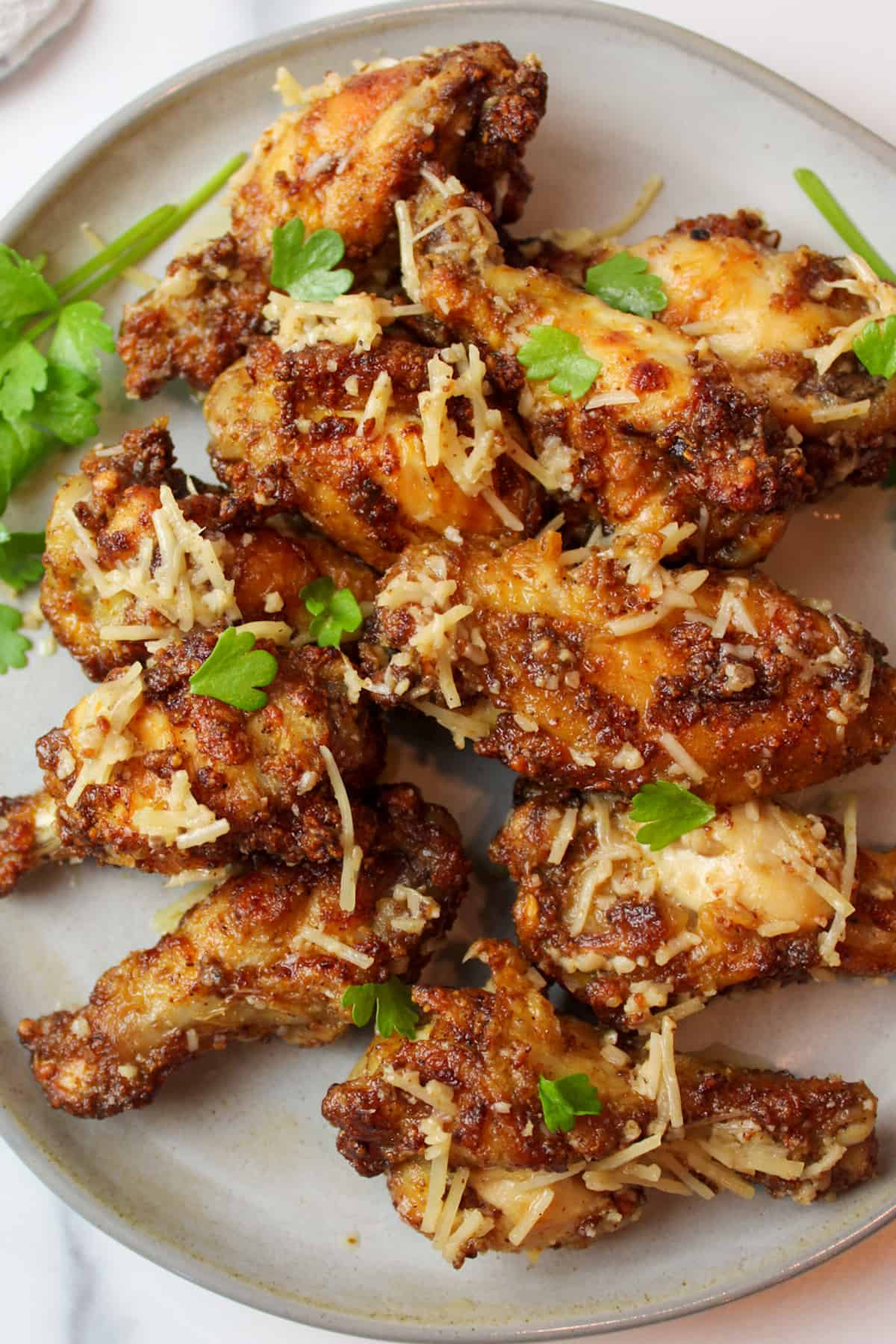 garlic parmesan wings on a plate with fresh parsley.