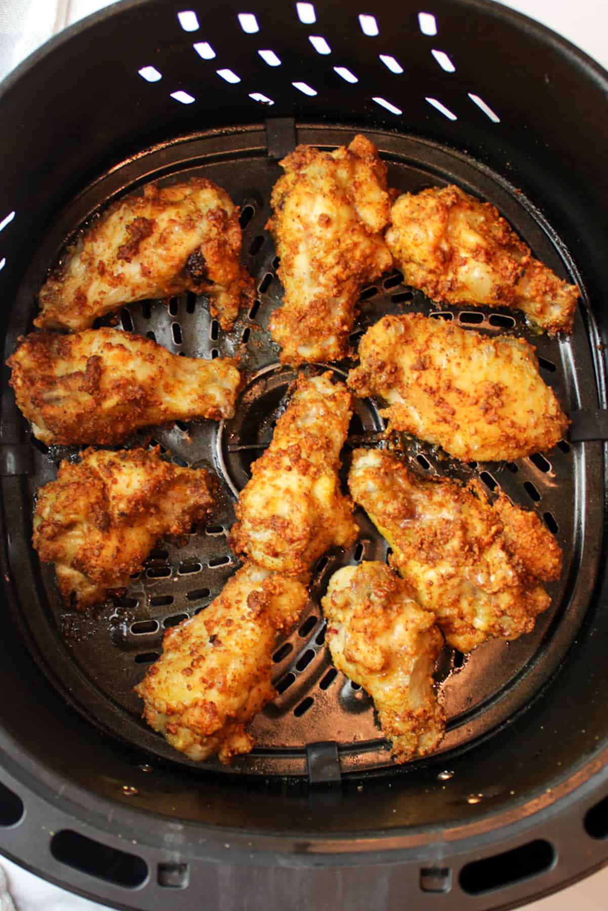 crispy chicken wings in an air fryer basket.