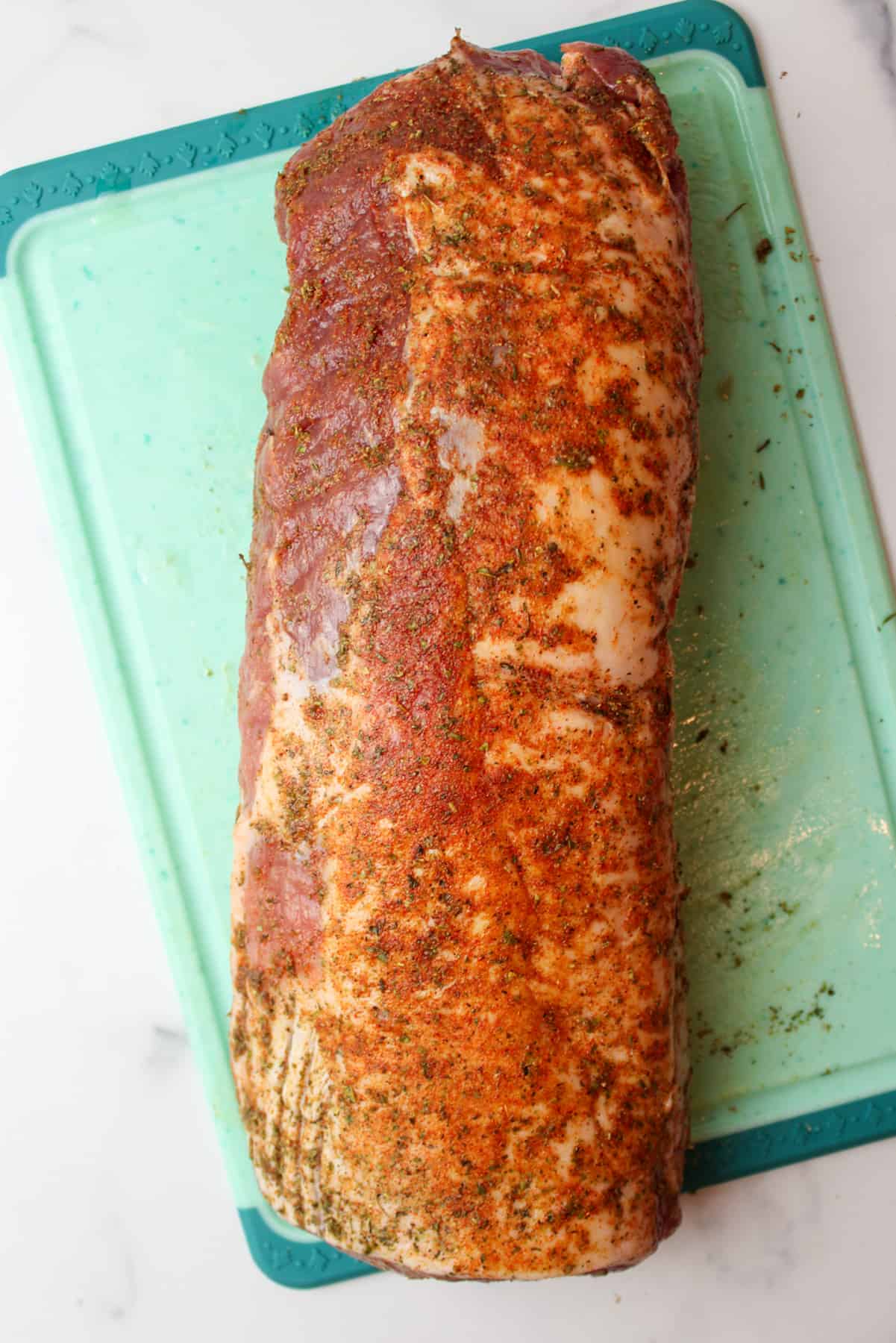 seasoning rubbed over pork loin on a cutting board.