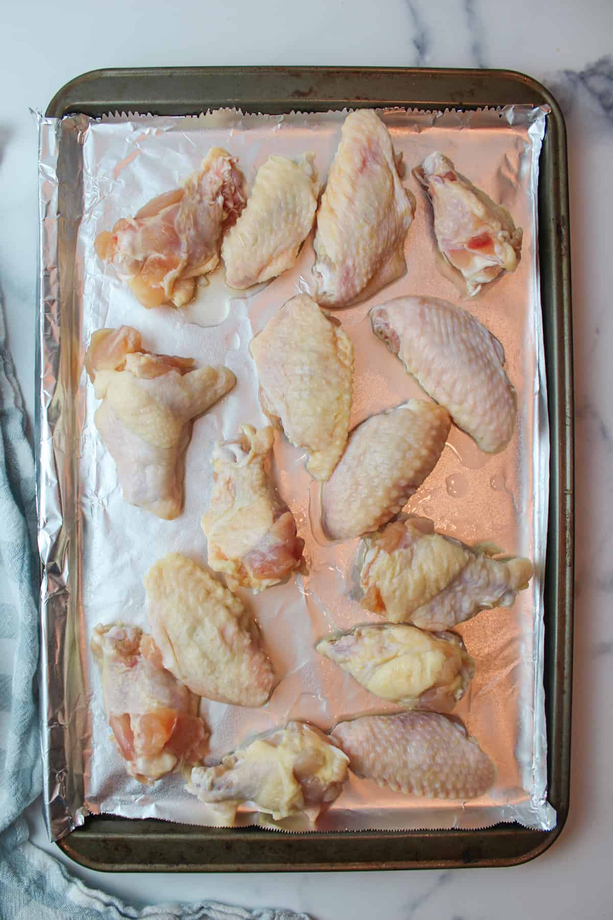 beer brined chicken wings on a foil lined baking sheet.
