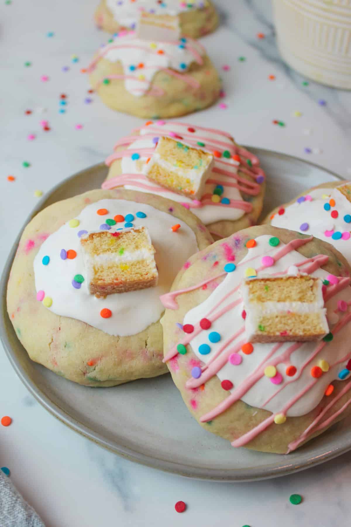 decorated birthday stuffed cookies on a plate with sprinkles scattered around