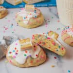 birthday cake stuffed cookies with one cookie cut in half and angled off of another cookie to reveal the soft inside texture