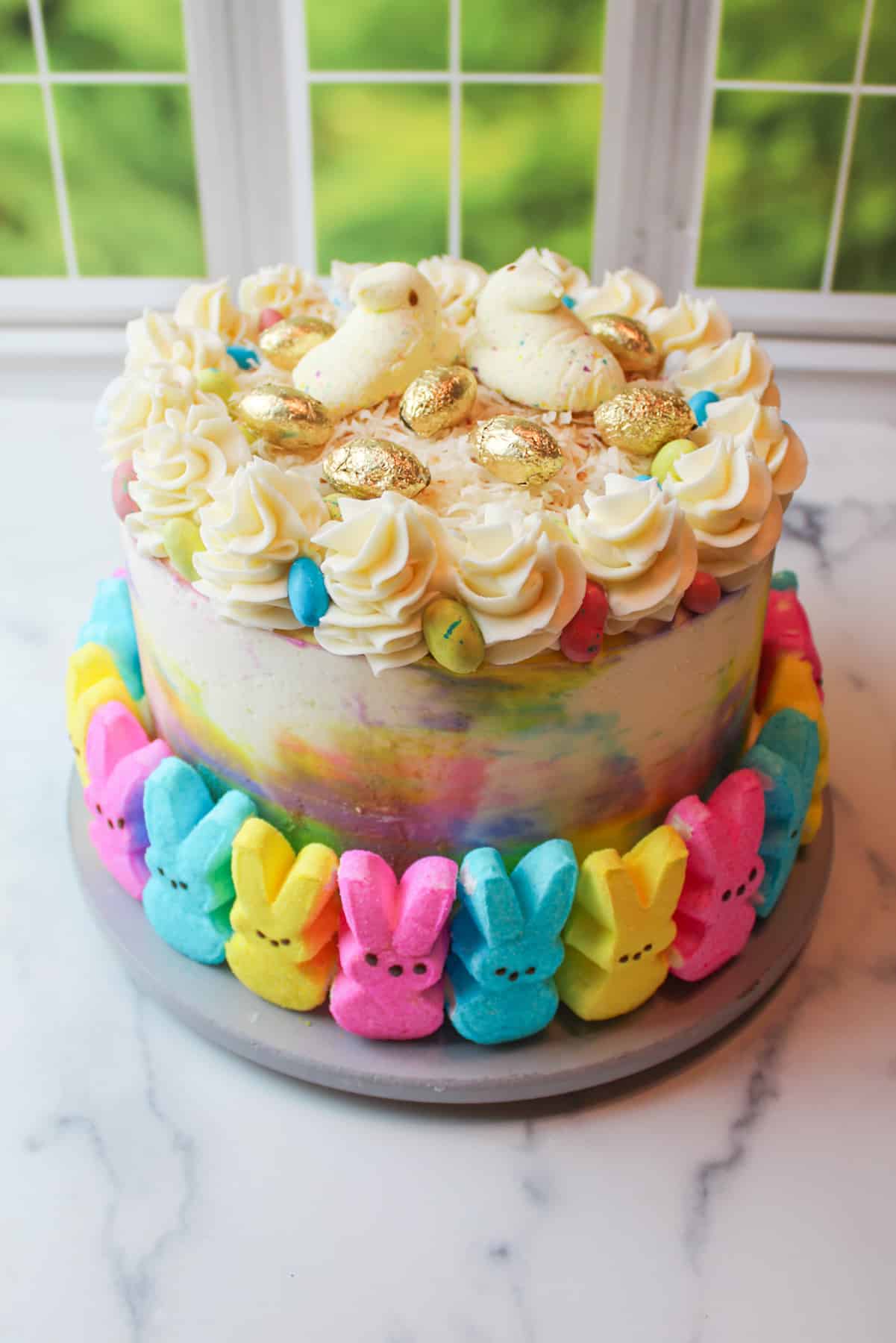 easter confetti cake ganished with peeps and easter egg candies.