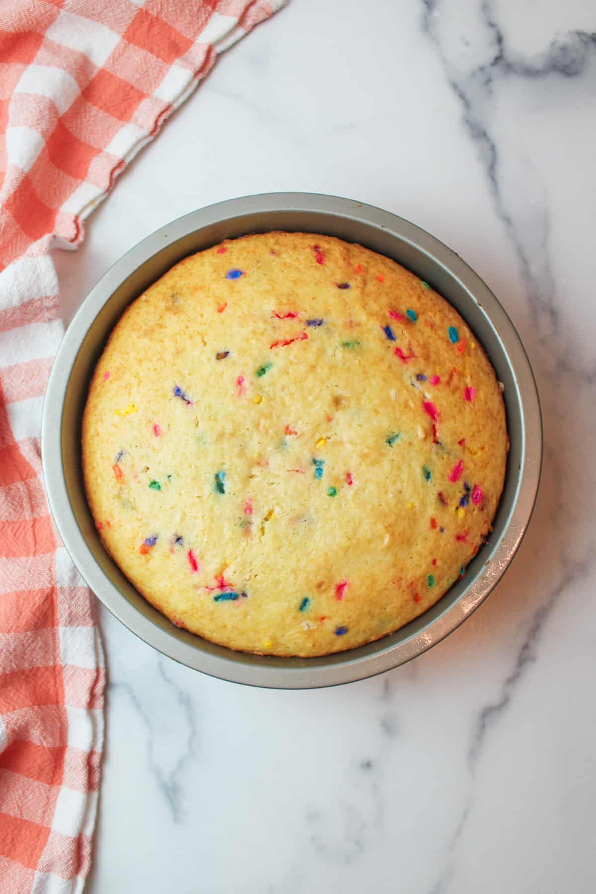 baked sprinkle cake in a round cake pan.