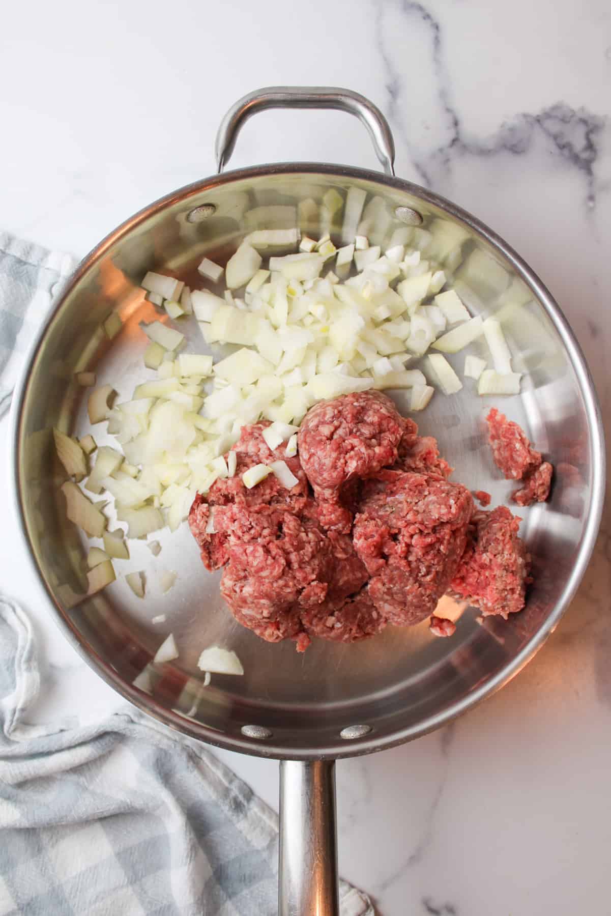 raw ground beef and diced onions in a skillet