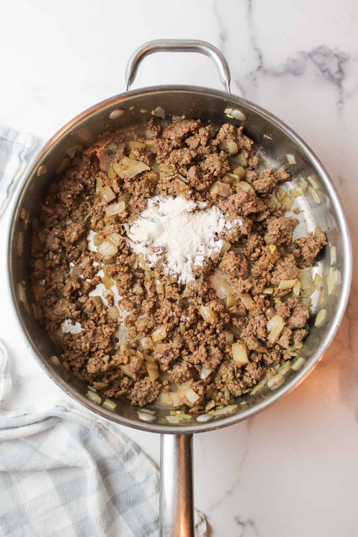 flour added to seasoned ground beef and onion mixture in a skillet