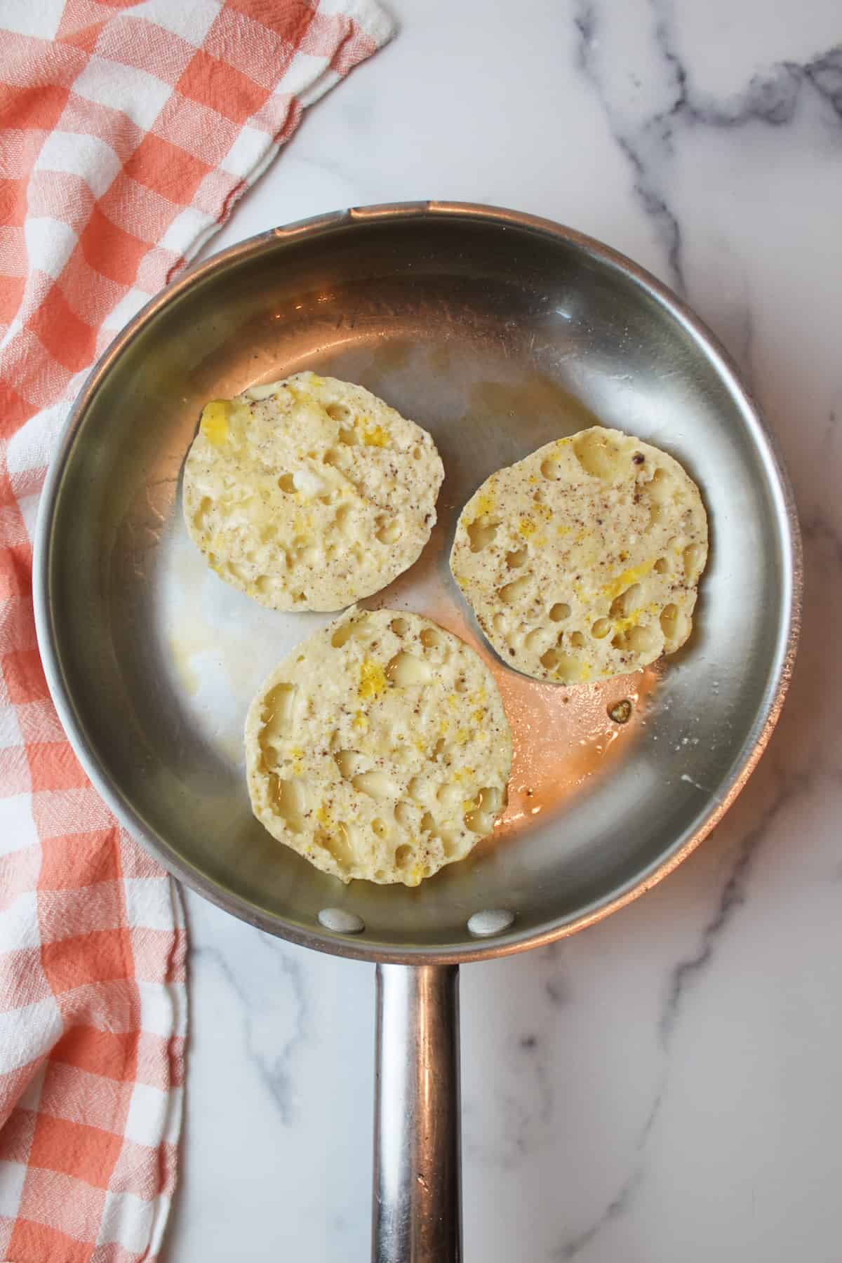 three french toast soaked english muffins in a greased skillet.