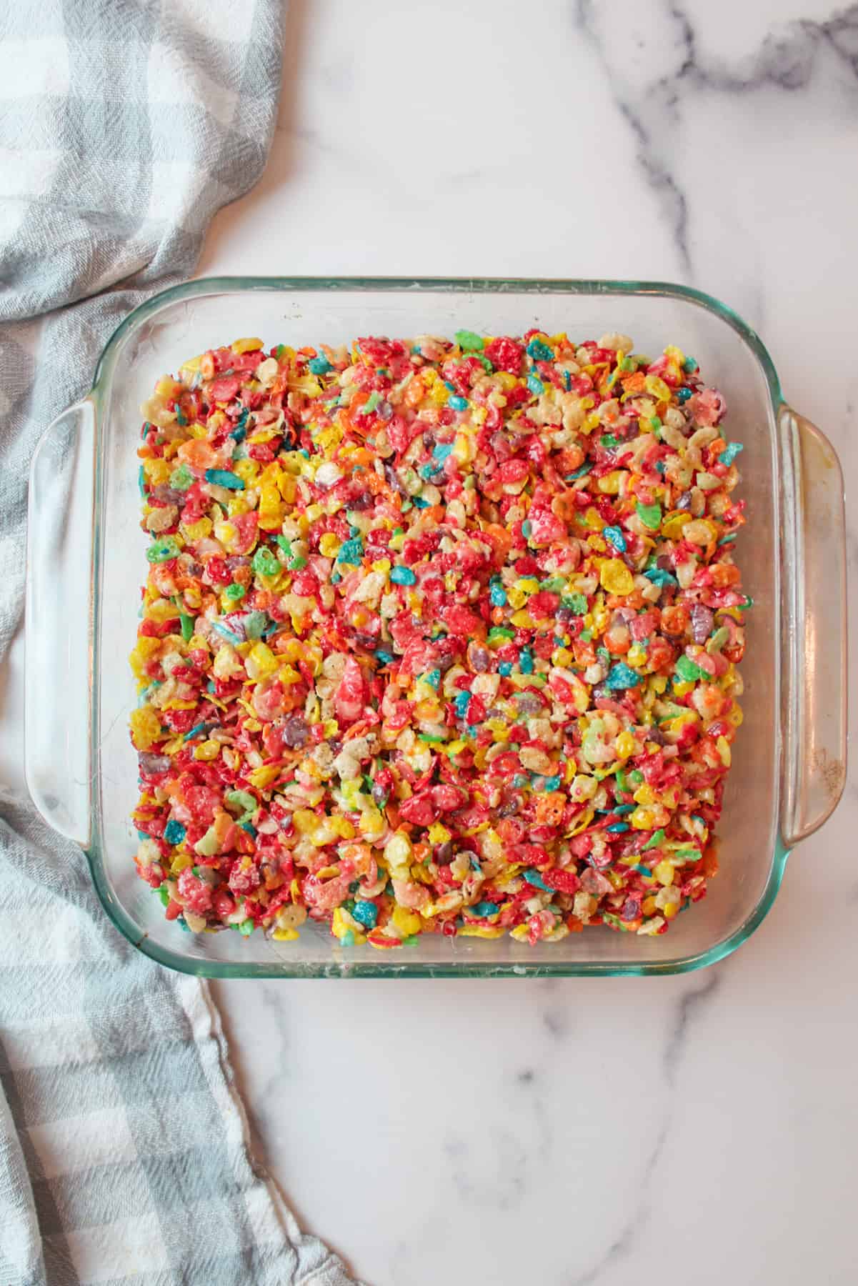 fruity pebbles treats in a square baking dish not cut yet.