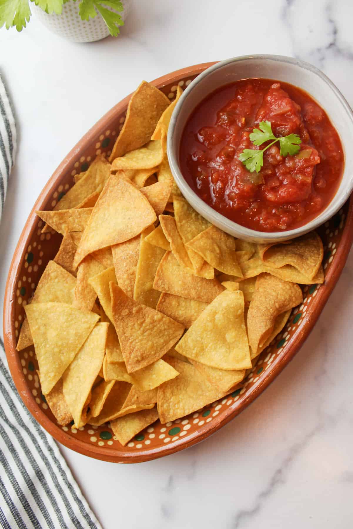 a plate of tortilla chips and a bowl of red salsa.