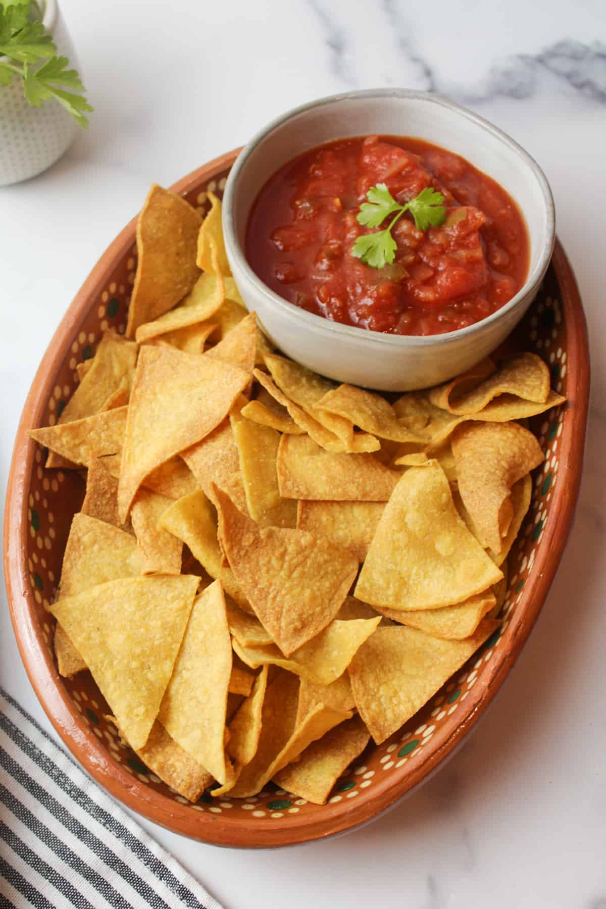 a plate of homemade tortilla chips and a bowl of red salsa