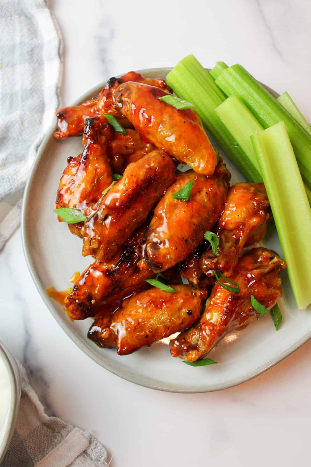 a plate filled with honey buffalo wings and sliced green celery.