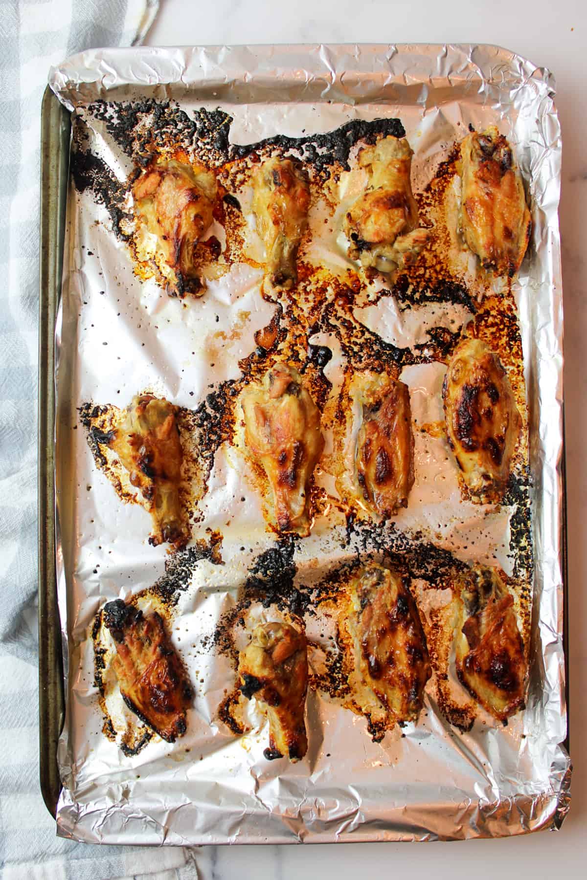 crispy broiled chicken wings on a foil lined baking sheet