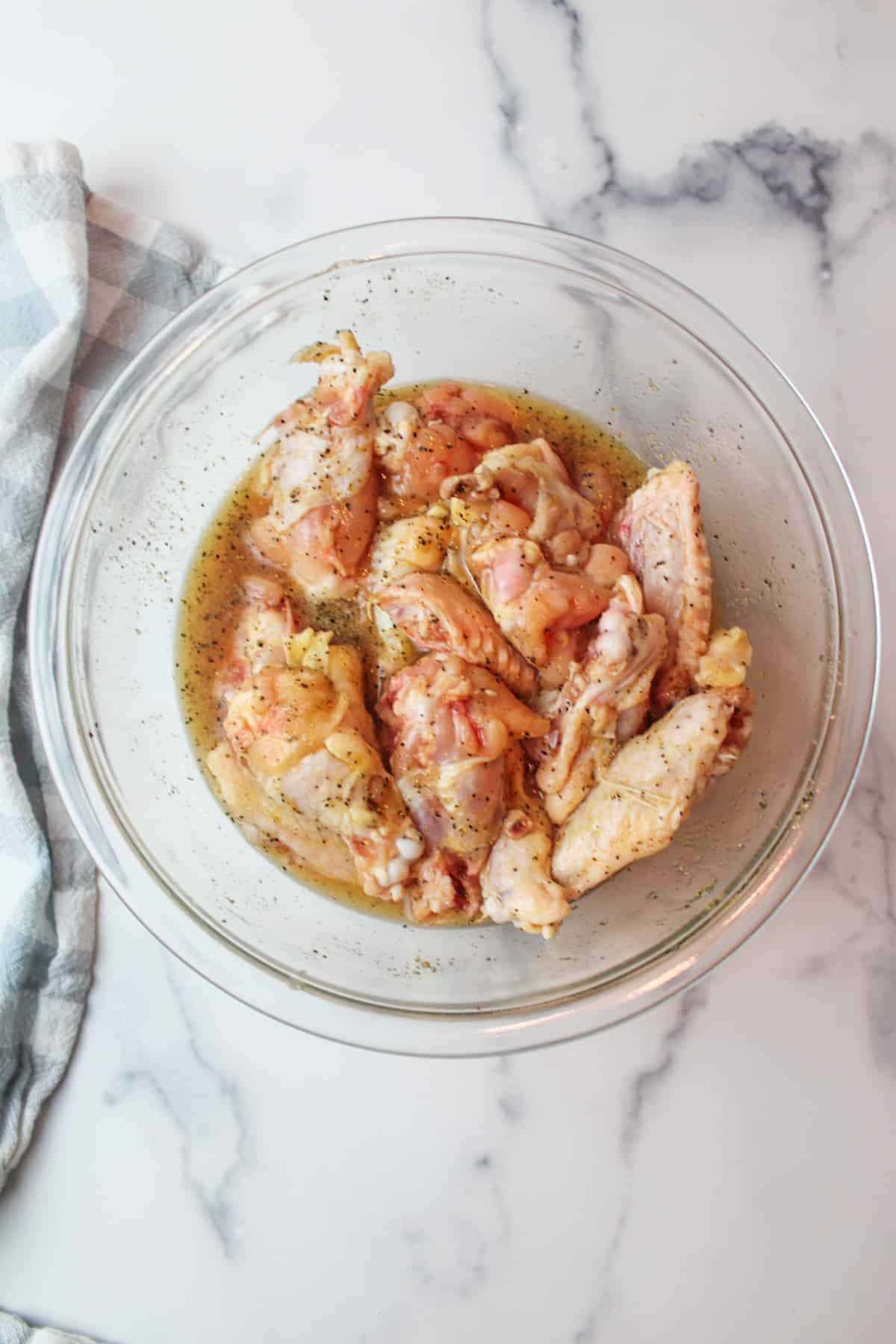 honey lemon pepper seasoning coated raw chicken wings in a mixing bowl.