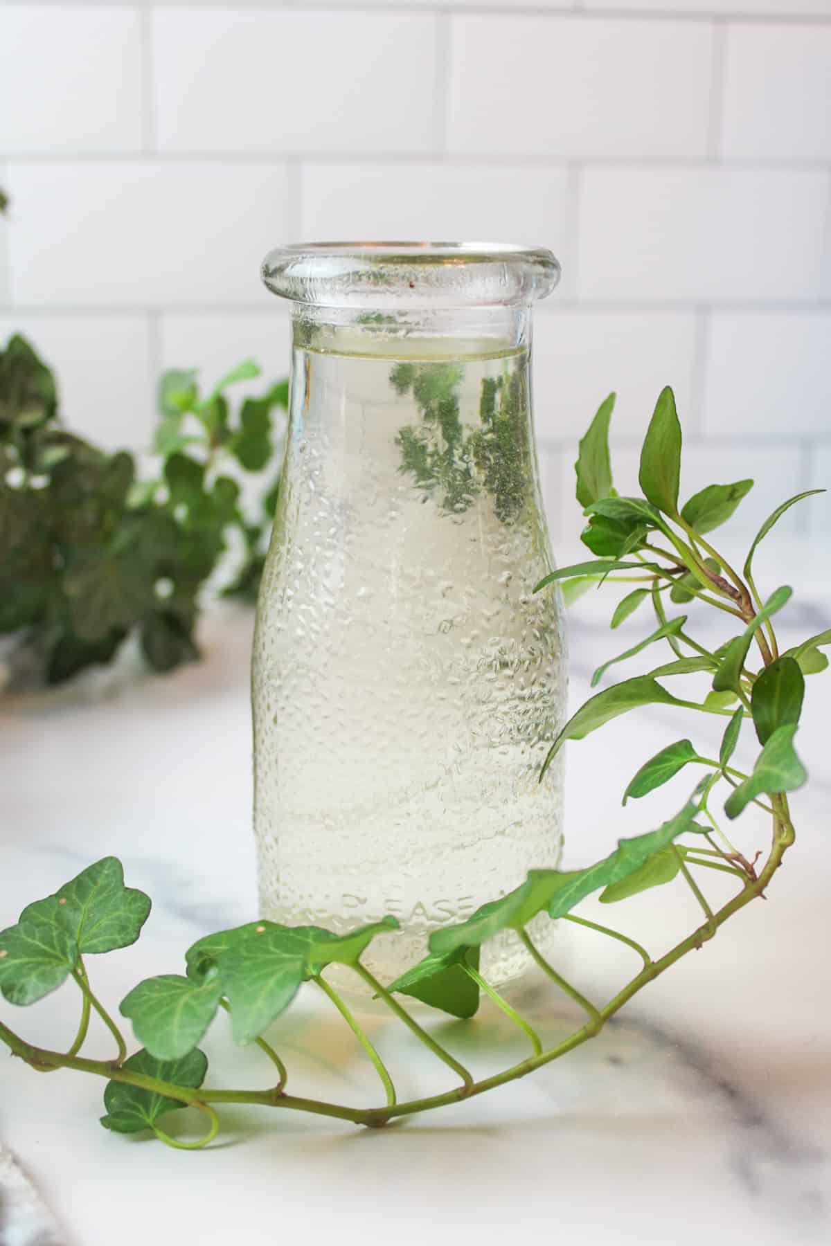 a glass bottle full of simple syrup with a reen leaf vine around it