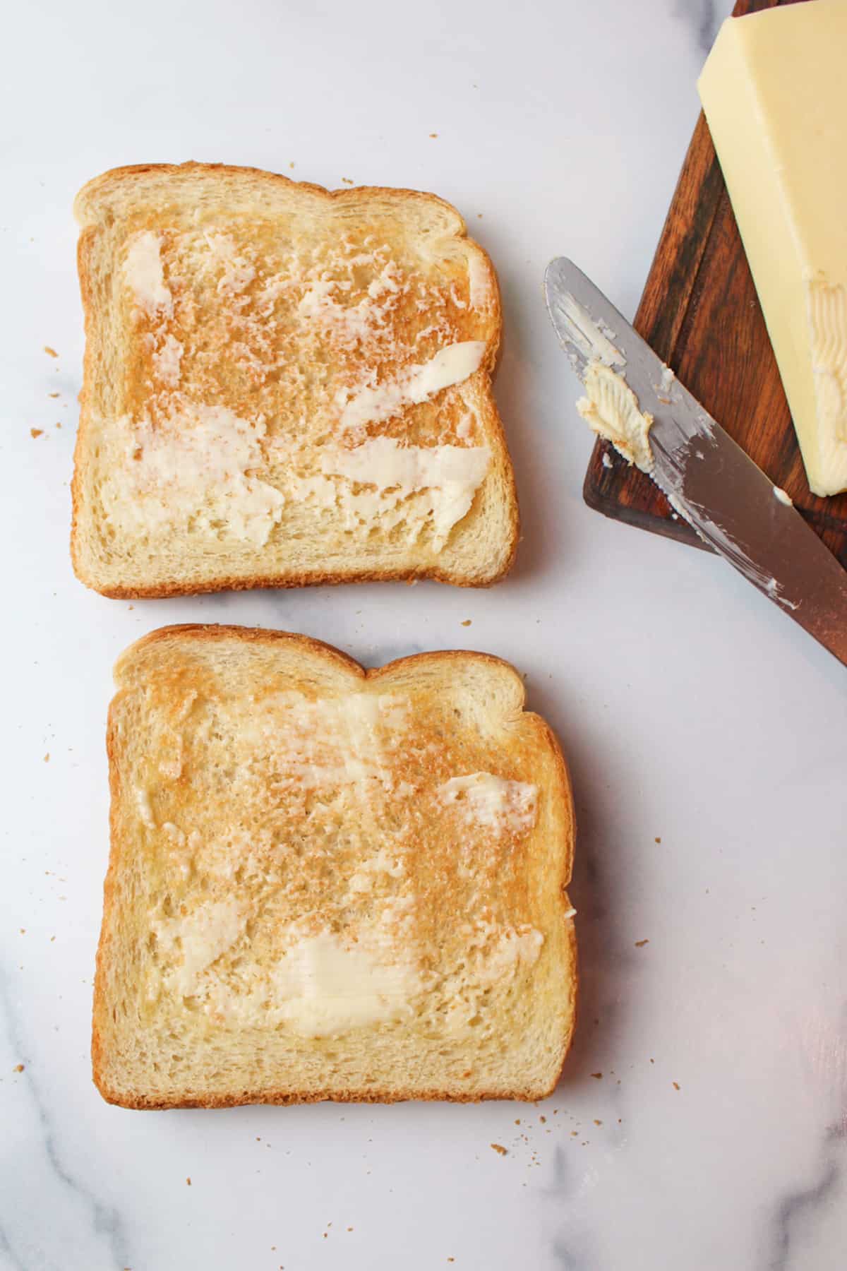 Butter spread on white bread toast with used knife aside.