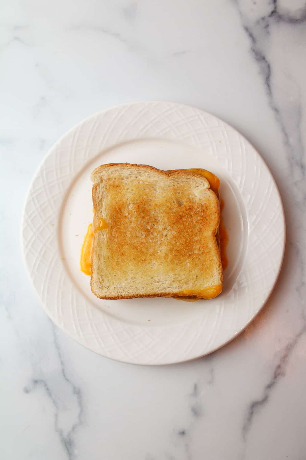 microwaved grilled cheese on a plate with melty cheese.