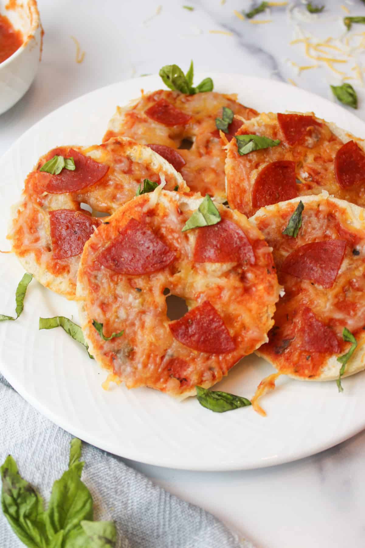 a plate of mini bagel pizzas with basil garnishes