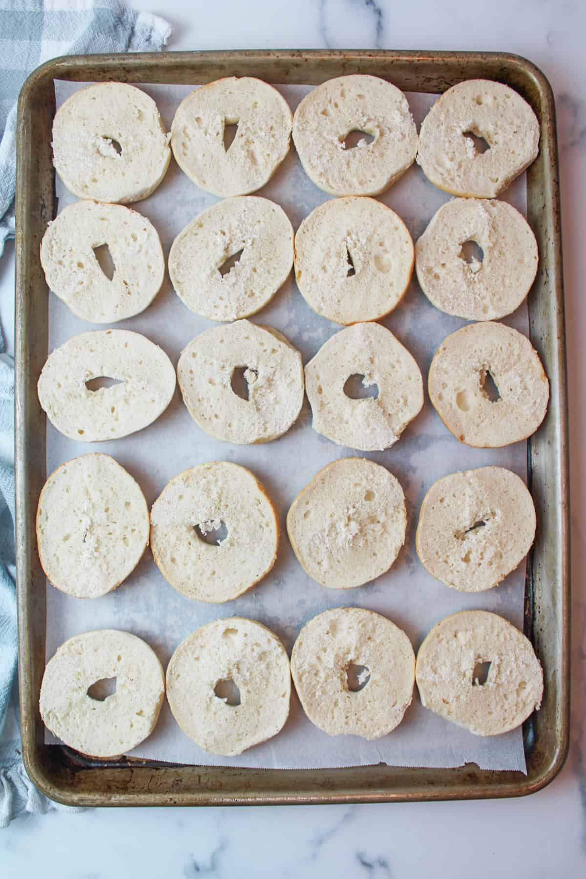 halved mini bagels on a parchment paper lined baking sheet