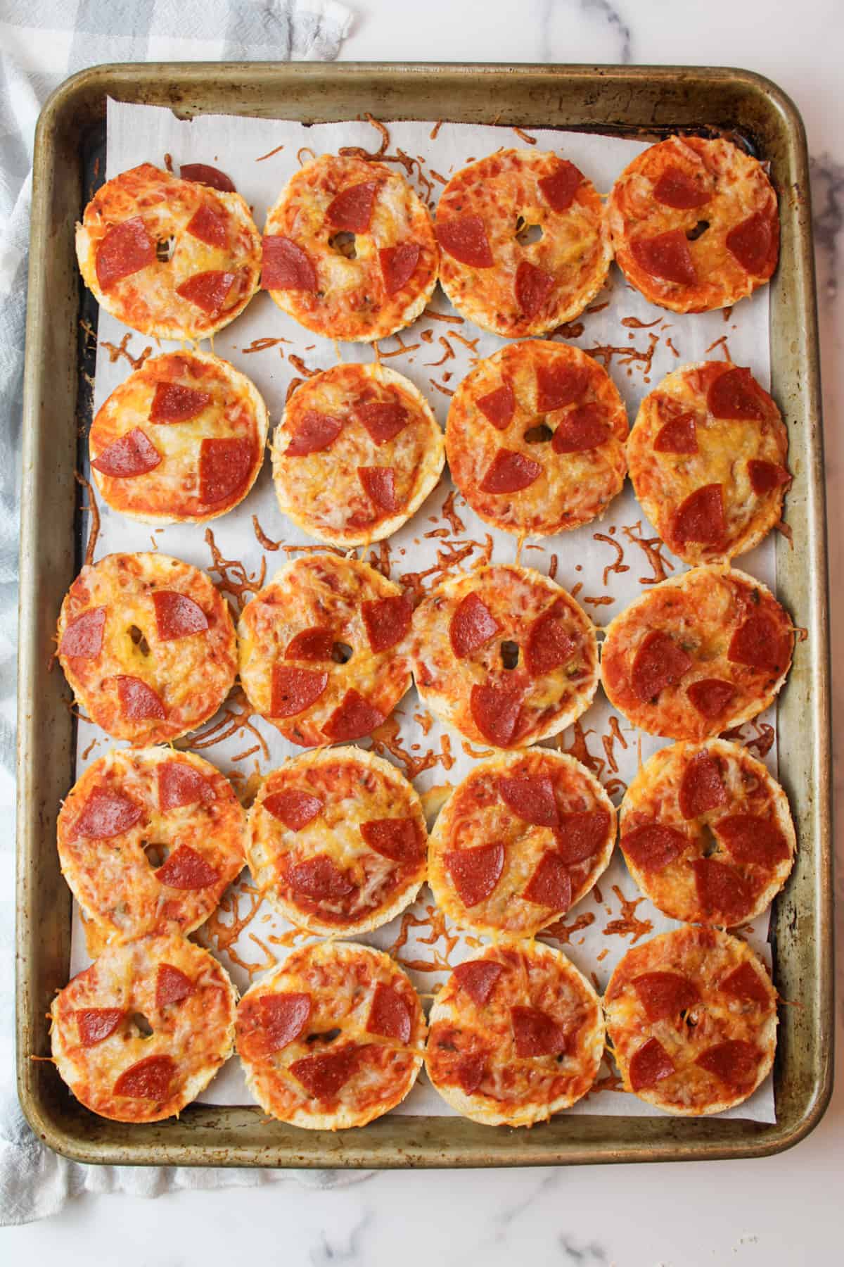 baked papperoni mini bagel pizzas on a parchment paper lined baking sheet