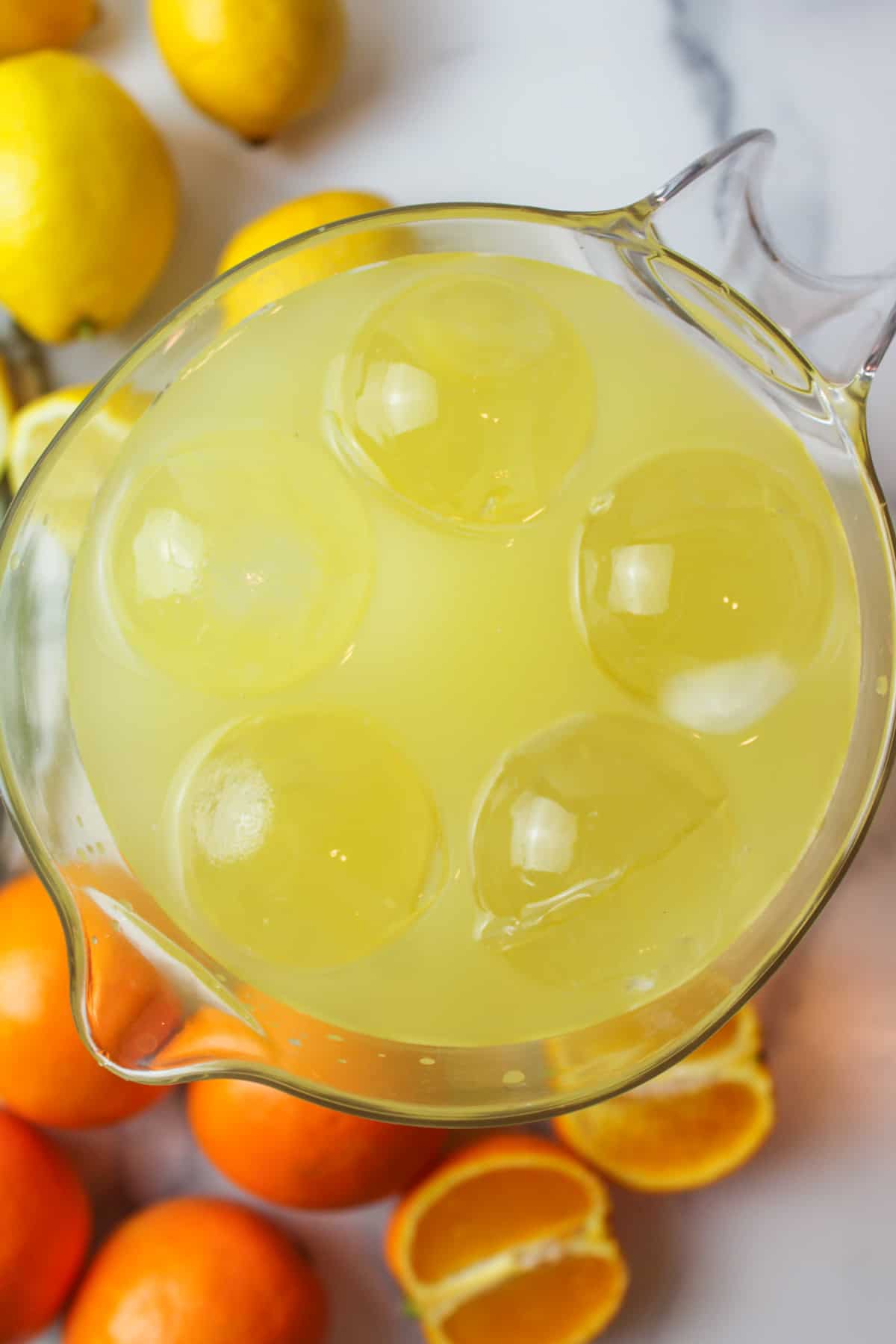 round ice cubes added to a pitcher full of orange lemonade