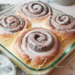 cinnamon rolls with icing on top in an 8x8 baking dish.