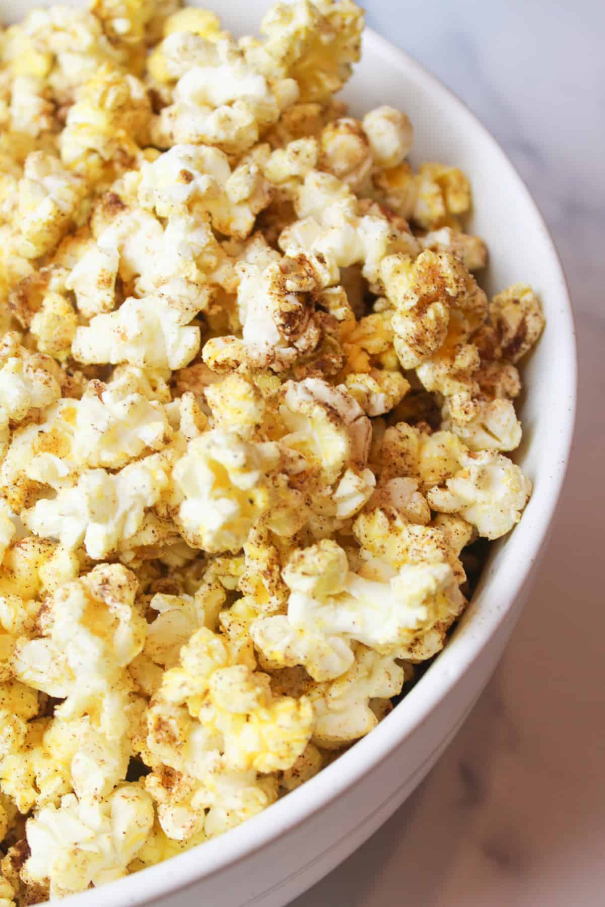 an upclose view of snickerdoodle popcorn in a lare white bowl