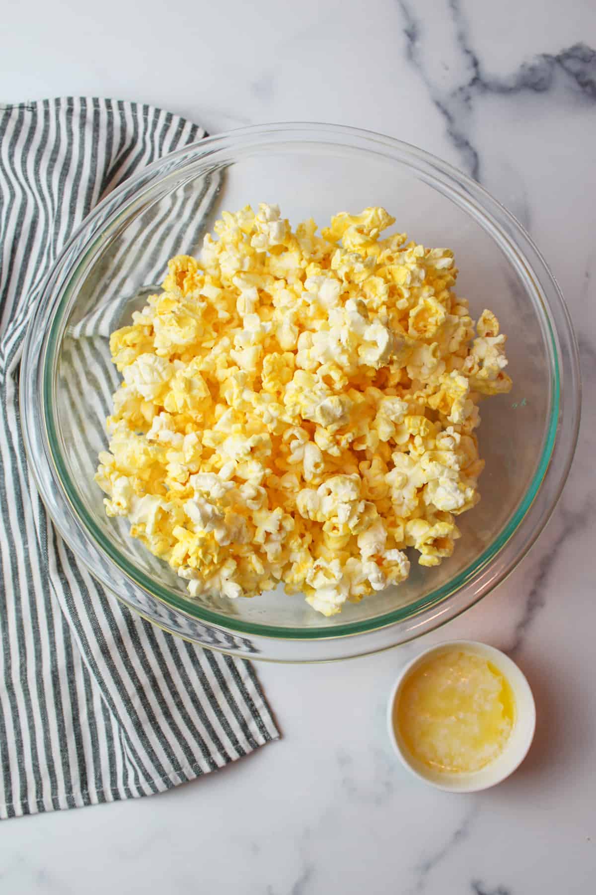 popped popcorn in a bowl with a bowl of melted butter to the side.