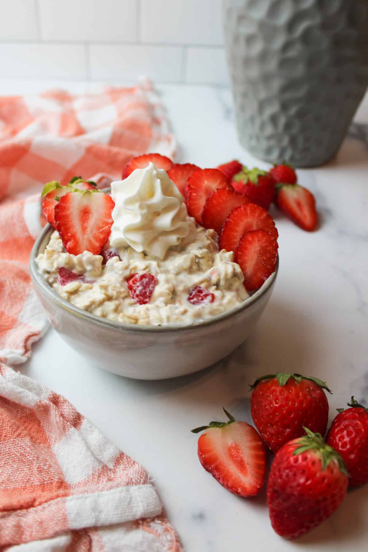 a bowl of strawberries and cream overnight oats with fresh strawberries and whipped cream on top