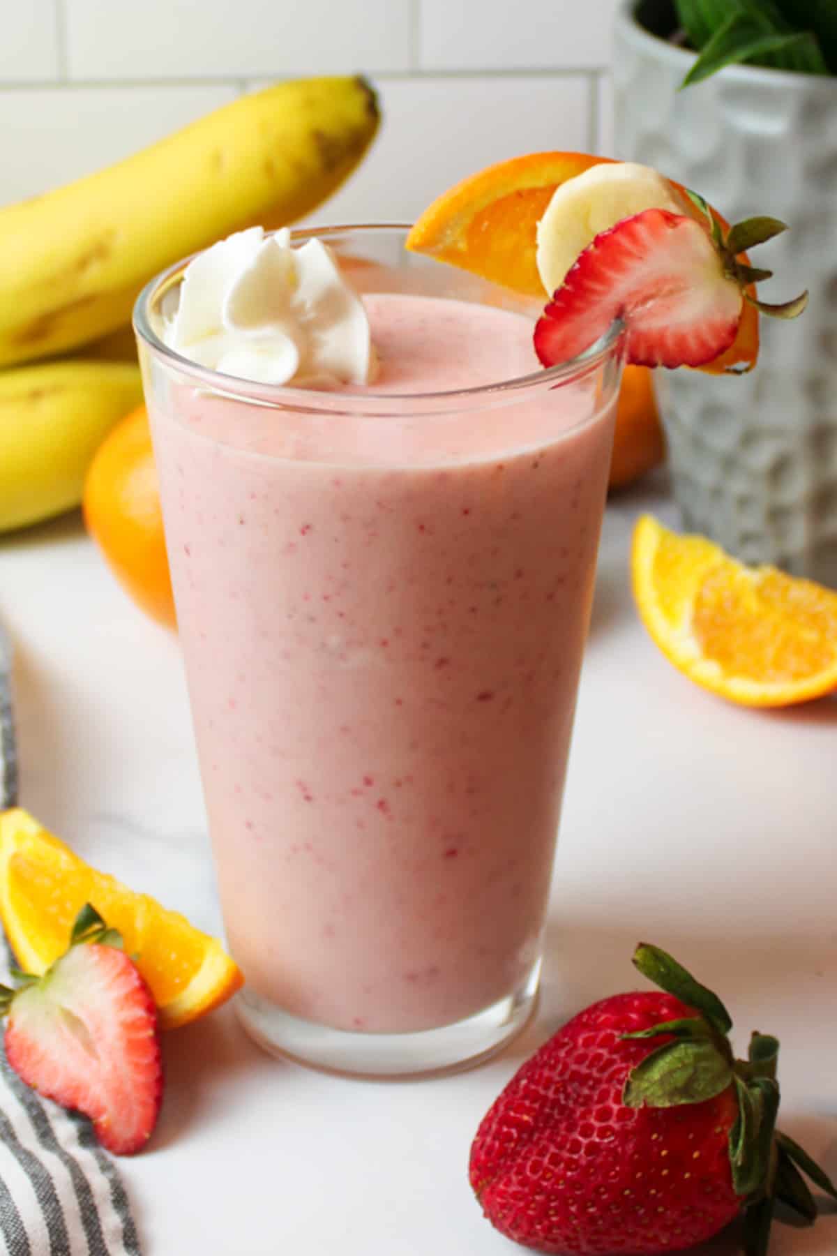 a cup of strawberry orange smoothie with fresh fruit garnishes.