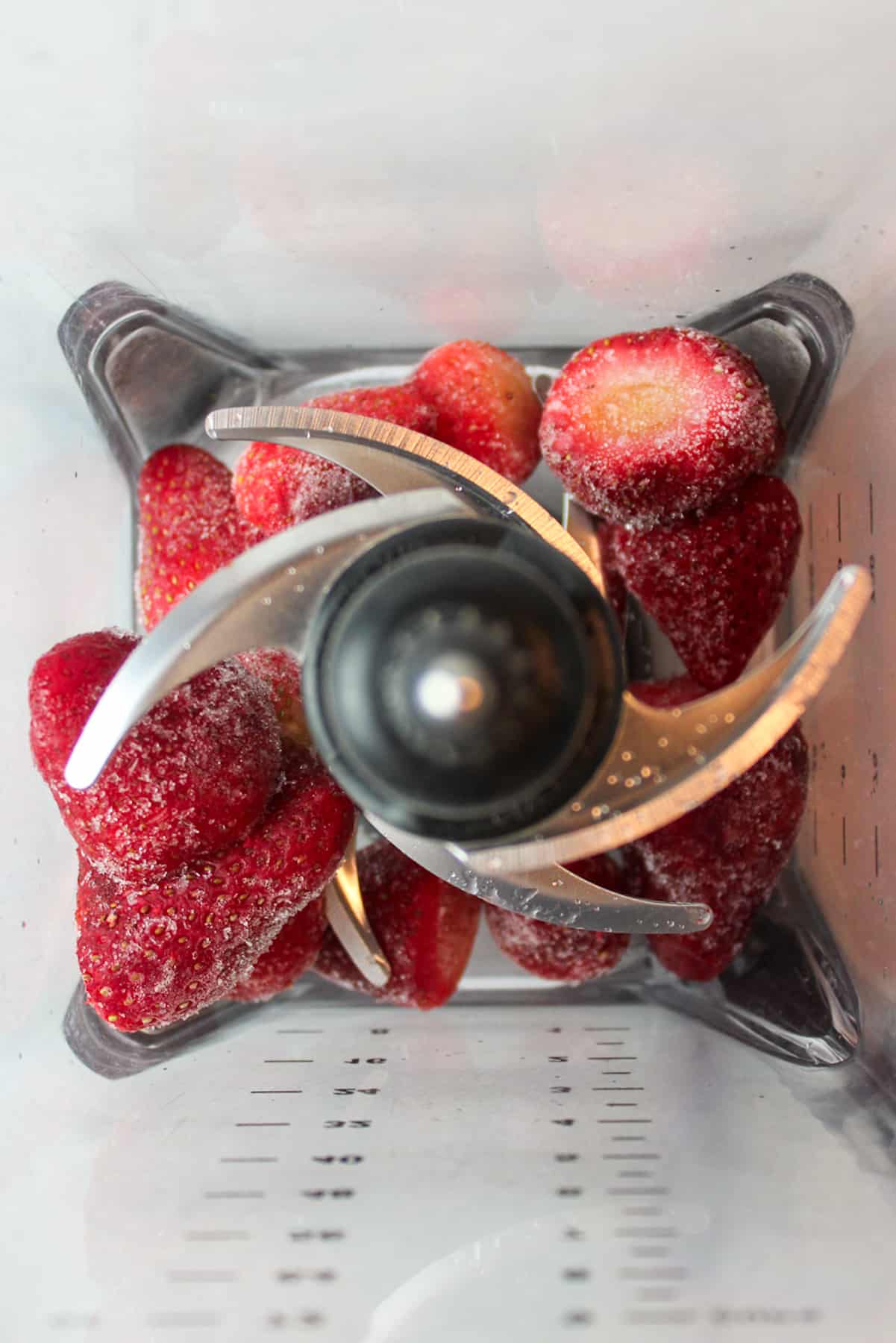aerial view into a blender with frozen strawberries inside