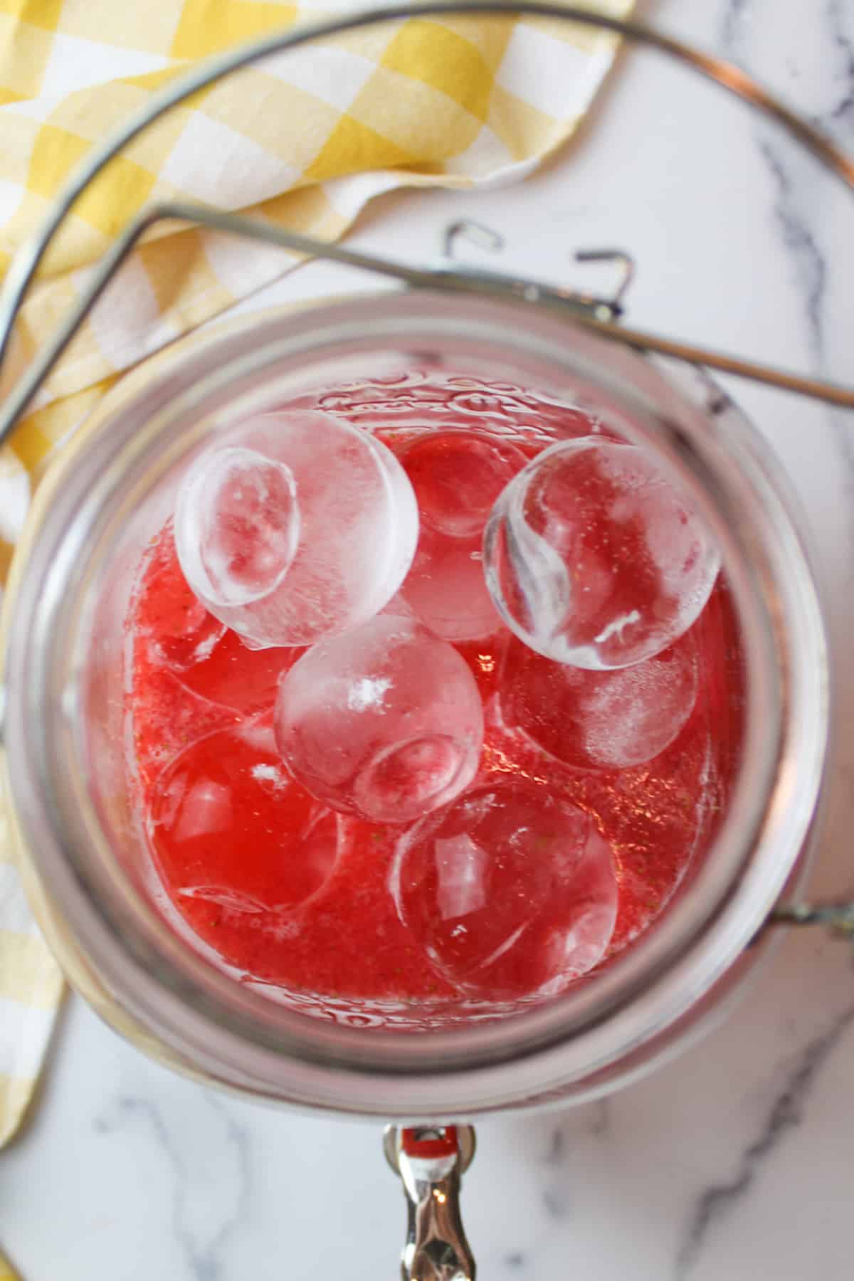 ice balls in a glass pitcher with strawberry puree and lemon juice.