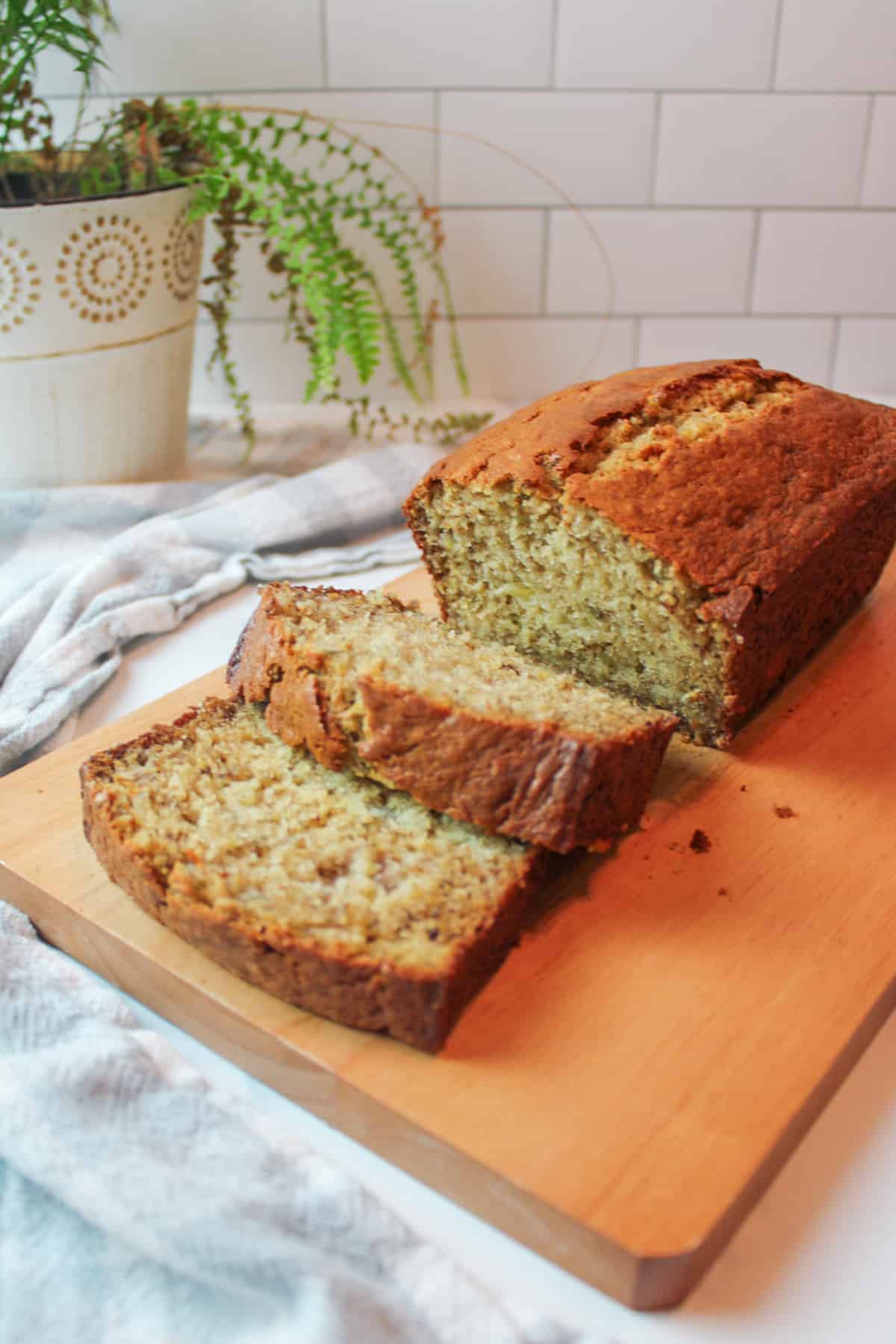 a sliced loaf of sour cream banana bread on a wooden cutting board.