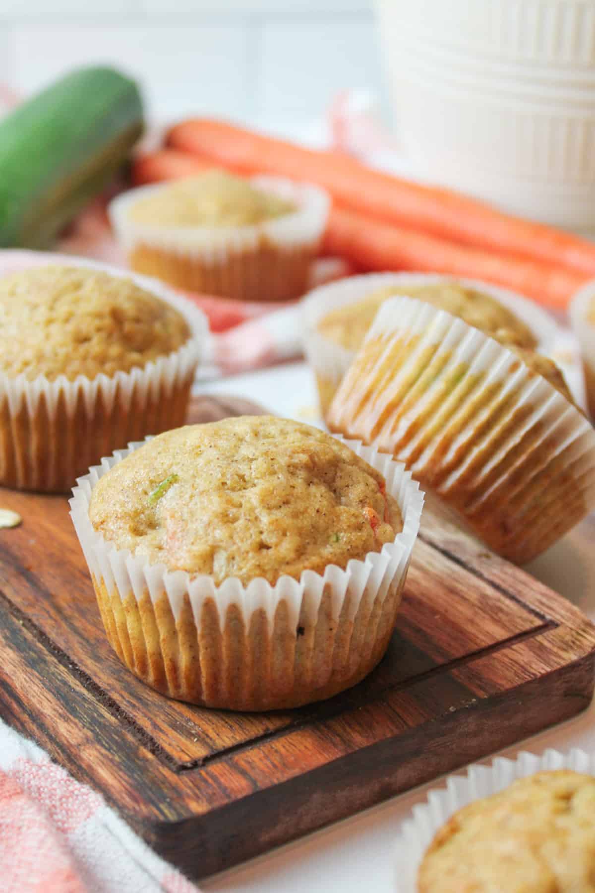 muffins on a wooden board with zucchini and carrot in background