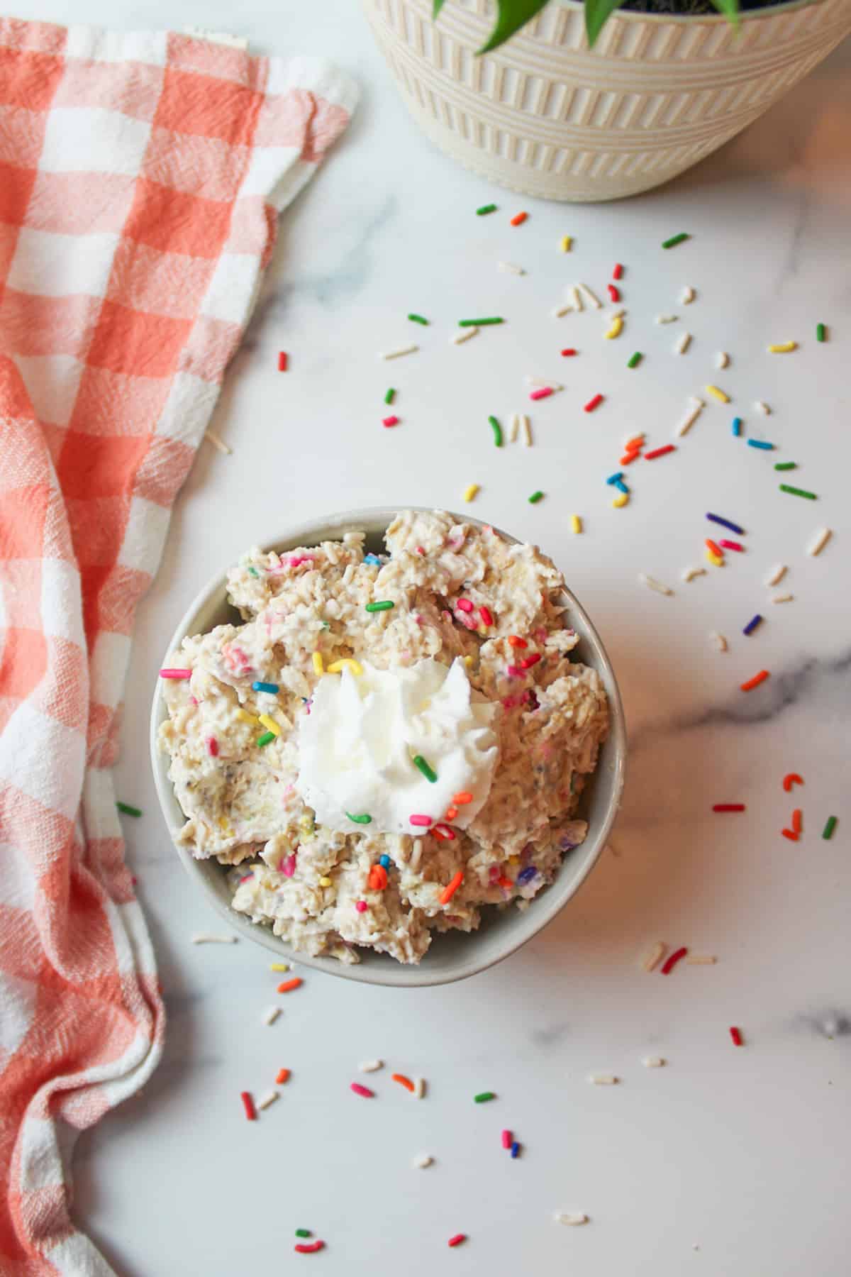 aerial view of a bowl filled with birthday cake oats and toped with whipped cream
