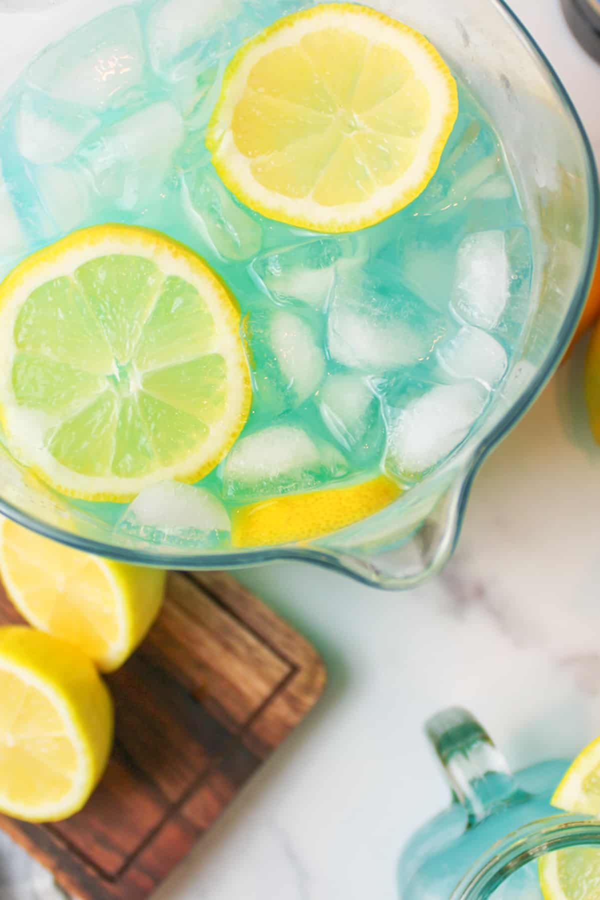 aerial view of a pitcher full of blue lemonade wnd ice garnished with lemon slices