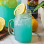 an upclose view of blue raspberry lemonade in a glass mug garnished with a slice of lemon