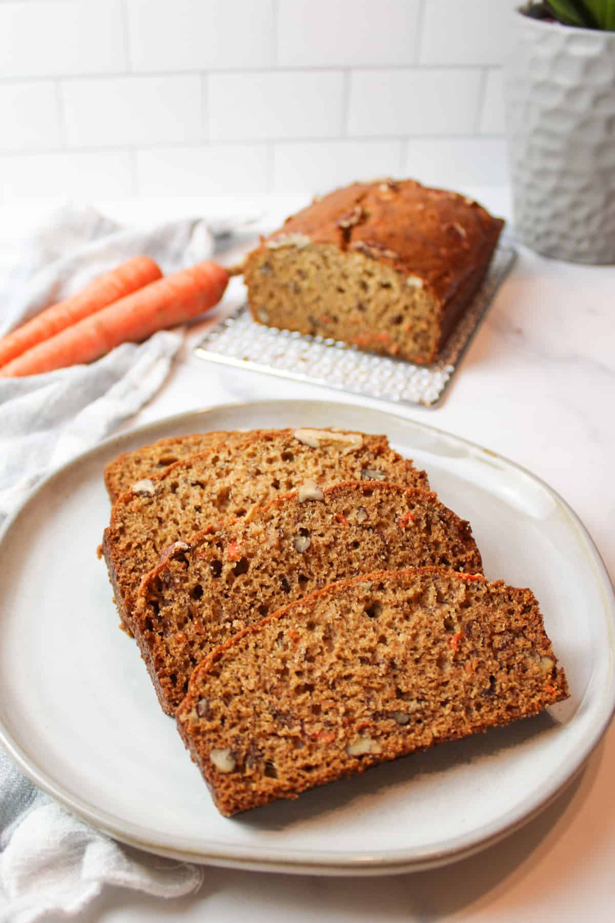 sliced carrot cake banana bread on a plate with carrots and more bread in background