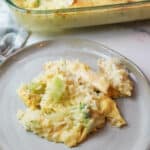 chicken broccoli rice casserole on a plate with more in a baking dish in the background.