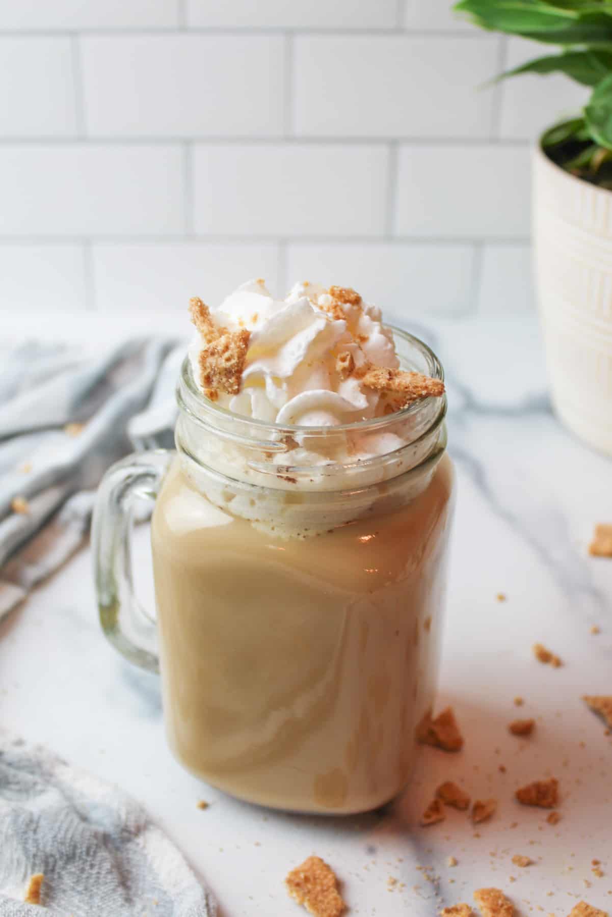 a glass mug full of cinnamon toast crunch latte with whipped cream and cereal on top.