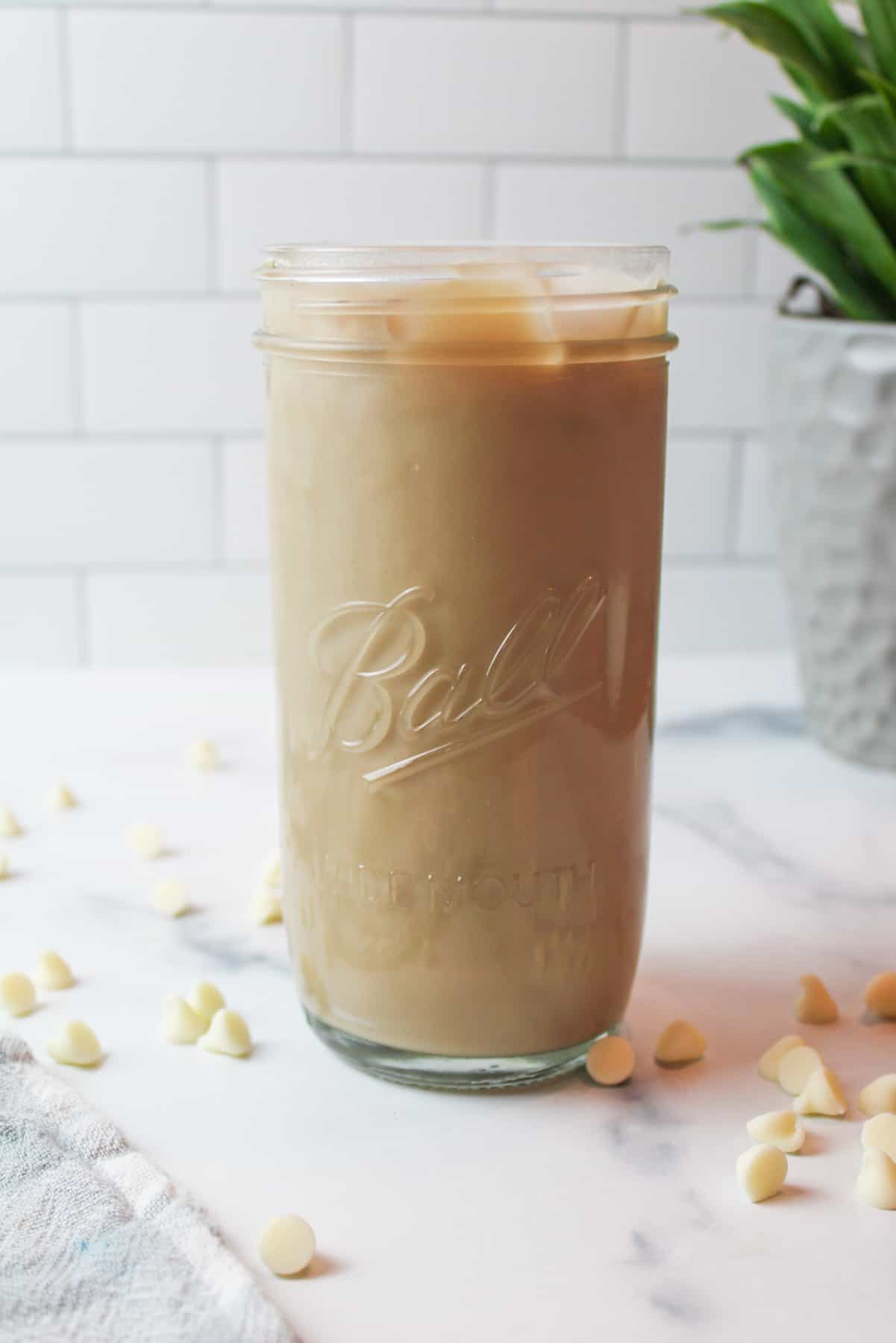 a tall glass of iced white mocha surrounded by white chocolate chips