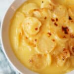an upclose view of au gratin potatoes in a white baking dish