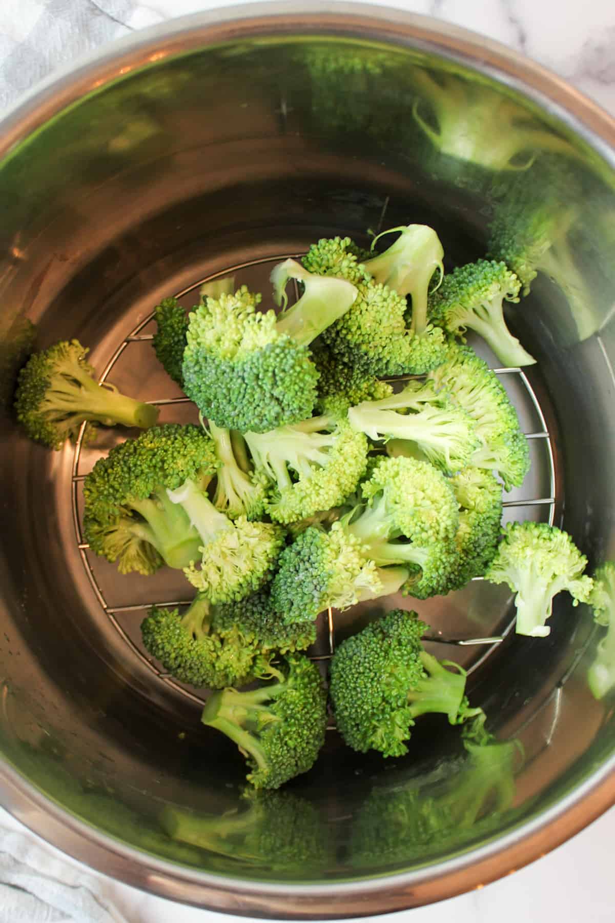 an instant pot with a trivet water and broccoli florets inside.