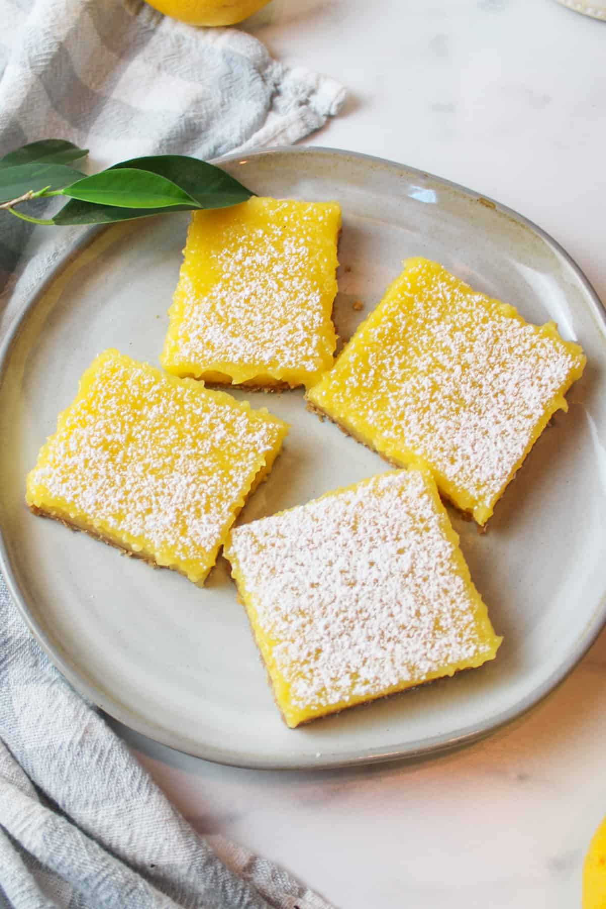 4 powdered sugar dusted squares of lemon bars on a plate