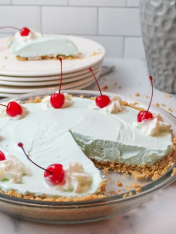 a close up of sliced kool aid pie topped with whipped cream and cherries